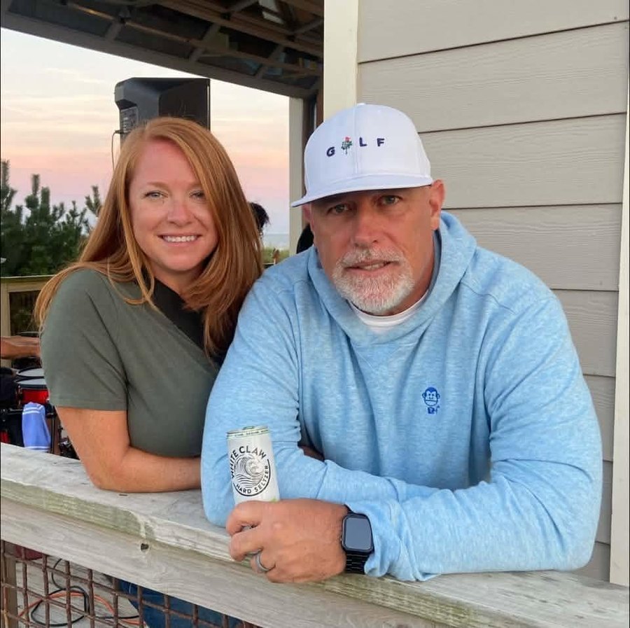 Bob Merryman and his wife at the beach pavilion, Golf Monkey hoodie on